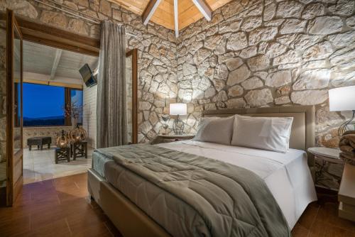 a bedroom with a large bed and a stone wall at Tramonto Villa in Volímai