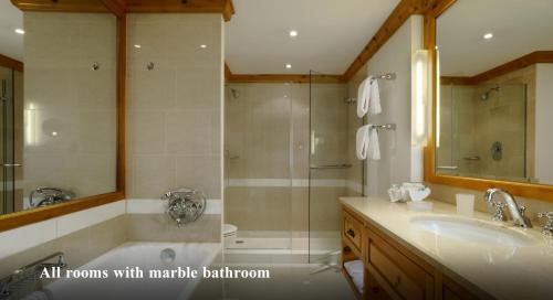 a bathroom with a tub and a shower and a sink at Crystal Hotel superior in St. Moritz