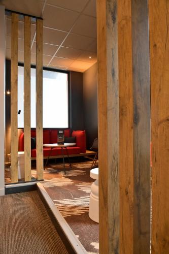 a living room with a red couch and a window at ibis Saint Quentin Basilique in Saint-Quentin