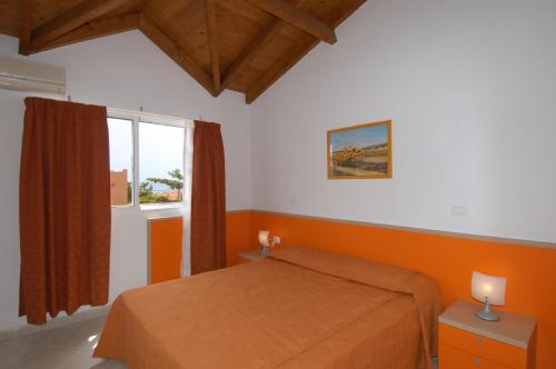 1 dormitorio con cama de color naranja y ventana en Aparthotel Ponta Preta, en Santa Maria