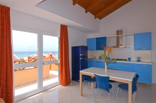 een keuken met blauwe kasten en een tafel met stoelen bij Aparthotel Ponta Preta in Santa Maria