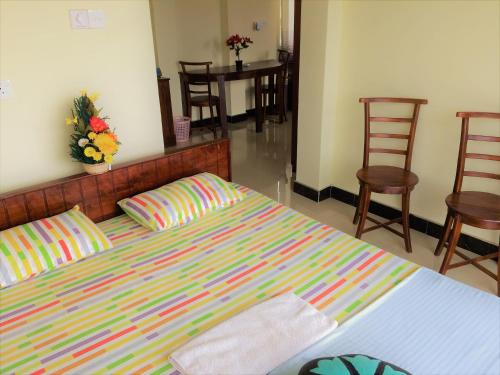 a bedroom with a bed with colorful sheets and chairs at Romeo and Juliet Guest House in Negombo