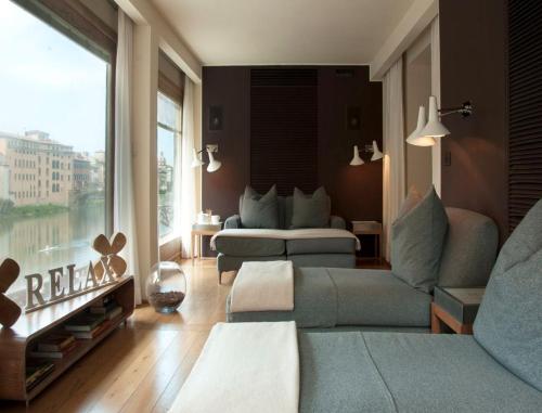 a living room with two couches and a large window at Hotel Continentale - Lungarno Collection in Florence