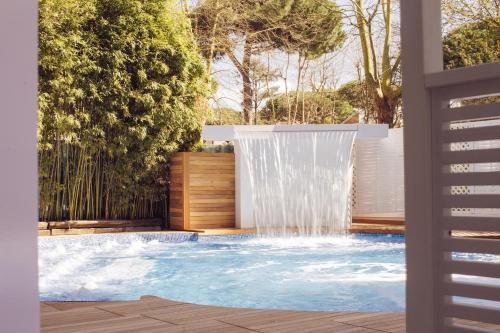 a waterfall in a backyard with a pool at Hotel Saraceno Resort with Private Beach in Milano Marittima