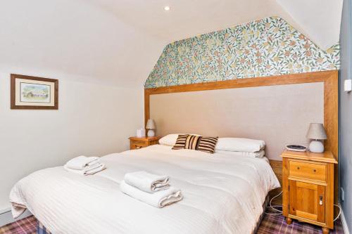 a bedroom with a large bed with white sheets at Duke of Wellington in Bourton on the Water