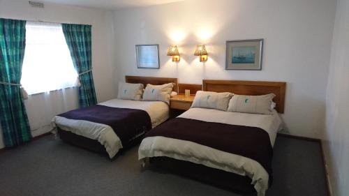 Habitación de hotel con 2 camas y ventana en Lamberts Bay Hotel, en Lambertʼs Bay
