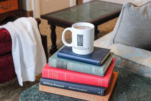 a stack of books with a cup of coffee on top at Hotel Providence in Providence