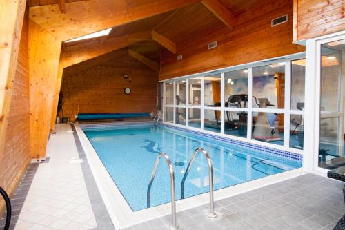 a swimming pool in a house with a wooden ceiling at Hunters Meet in Bishops Stortford