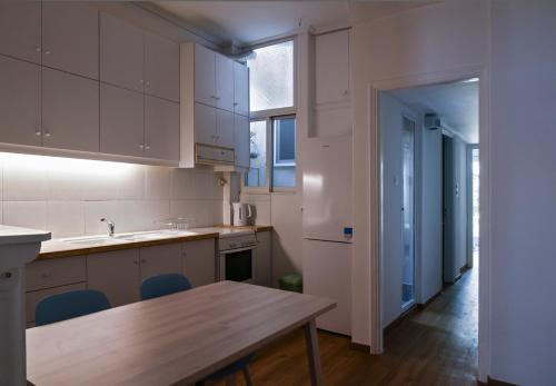 a kitchen with white cabinets and a wooden table at Miranda's Apartment in Thissio in Athens