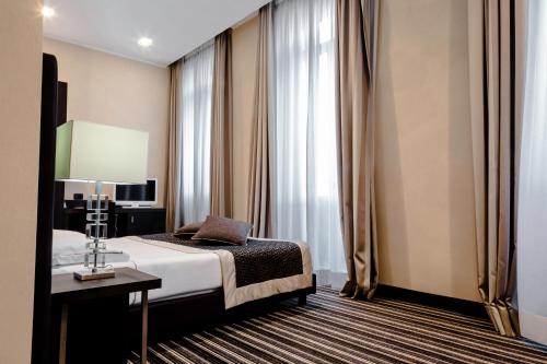 a hotel room with a bed and a table at Hotel Principe Di Torino in Turin