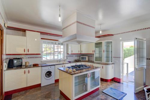 a large kitchen with white cabinets and a stove top oven at Villa Menir in Lagoa