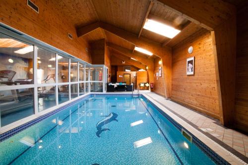 een groot zwembad in een groot gebouw met een zwembad bij Hunters Meet in Bishops Stortford
