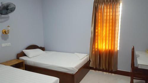 a room with two beds and a window with a curtain at KampongBay Makeng II Guesthouse in Kampot