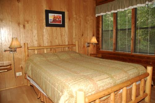 una camera da letto con un letto in una stanza con pareti in legno di Carolina Landing Camping Resort Deluxe Cabin 4 a Fair Play
