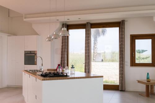 a kitchen with white cabinets and a large window at Lalena's Garden in Portopalo