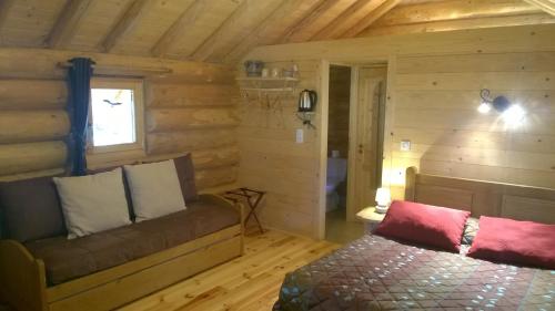 Habitación con cama y ventana en una cabaña de madera en Chambres d'hôtes La Gargaille, en Alièze