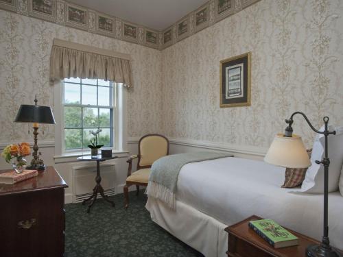 a bedroom with a bed and a desk and a window at Jared Coffin House in Nantucket