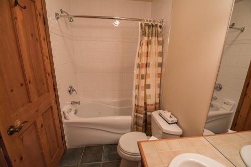 a bathroom with a tub and a toilet and a sink at Cap Tremblant Mountain Resort in Mont-Tremblant