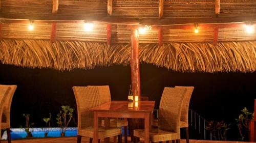 a table and chairs with a table and a straw umbrella at La Pintada Inn in La Pintada