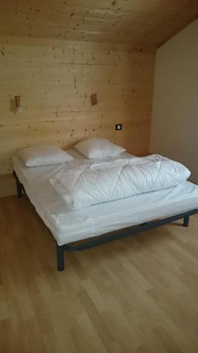 un lit avec des draps blancs et des oreillers dans une chambre dans l'établissement camping du haut des bluches, à La Bresse