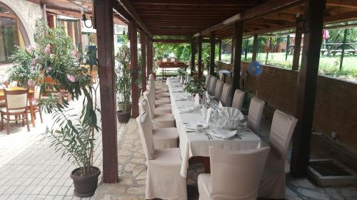 uma fila de mesas e cadeiras brancas num restaurante em Туристически комплекс"Странджа" em Sredets