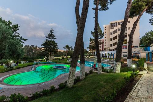a swimming pool in a park with trees at Menzeh Zalagh City Center in Fès