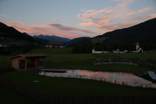 a sunset over a small lake in a field at App Unterhoezlhof in Valdaora