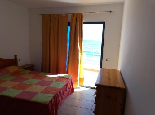 Puerto de las LajasにあるAPARTAMENTO PRIMERA LÍNEA DE PLAYAのベッドルーム1室(ベッド1台付)、海に面したドアが備わります。