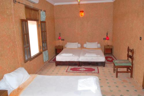 a bedroom with two beds and a chair in it at Gite Souss in Oulad Teima