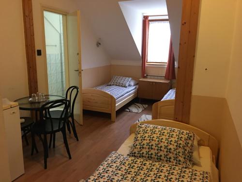 een kleine kamer met een tafel, een bed en een raam bij Termál Vendégház in Veresegyház