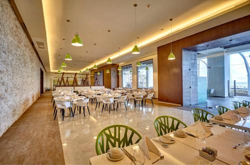 a restaurant with white tables and chairs and windows at Royalton Negril, An Autograph Collection All-Inclusive Resort in Negril
