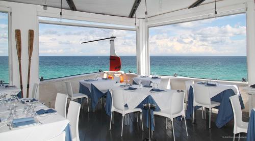 a restaurant with white tables and chairs and the ocean at I Sottani in Monopoli