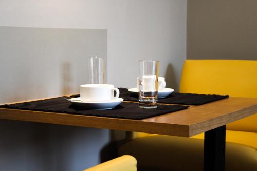 a wooden table with two cups and plates on it at Apartamentos Turisticos Paraiso in Funchal