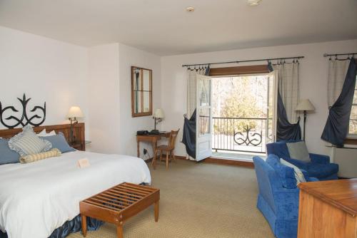 a bedroom with a bed and chairs and a window at Benmiller Inn & Spa in Goderich
