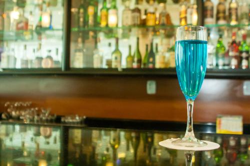 a glass of blue wine sitting on a bar at Leques Brasil Hotel Escola in Sao Paulo