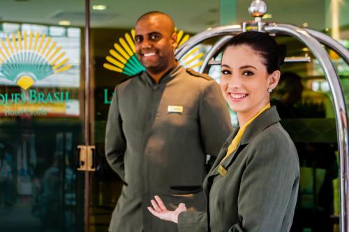 a man and a woman standing in front of a restaurant at Leques Brasil Hotel Escola in Sao Paulo
