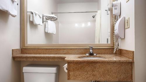 a bathroom with a sink and a mirror and a toilet at Best Western White Mountain Inn in Franconia