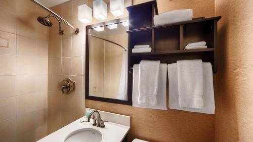 a bathroom with a sink and a mirror and towels at Best Western Watertown/Fort Drum in Watertown