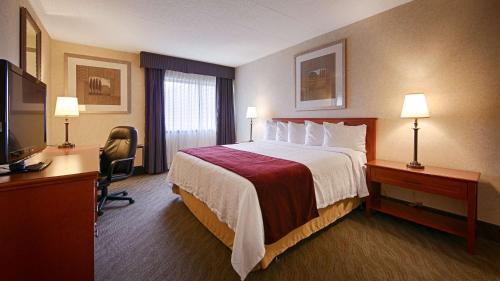 Habitación de hotel con cama, escritorio y TV. en Best Western North Bay Hotel & Conference Centre en North Bay