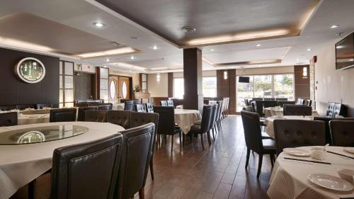 a restaurant with tables and chairs and a clock on the wall at Best Western PLUS Burnaby Hotel in Burnaby