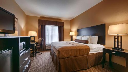 a hotel room with a bed and a flat screen tv at Best Western Bastrop Pines Inn in Bastrop