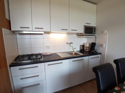 a small kitchen with white cabinets and a sink at DUINZICHT 6 Bed by the Sea in Westkapelle