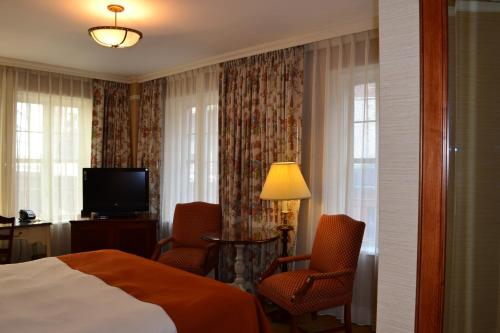 a hotel room with a bed and two chairs and a television at The Wall Street Inn in New York