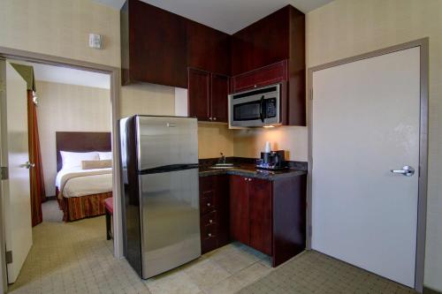 a kitchen with a refrigerator and a bed in a room at Best Western Plus Bowmanville in Bowmanville