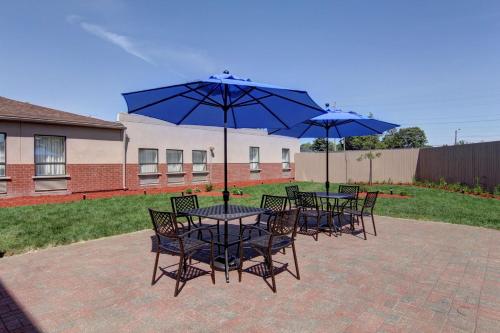 a group of tables and chairs with blue umbrellas at Best Western Plus Bowmanville in Bowmanville