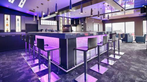 a bar with purple stools in a room at Hotel Levesque in Rivière-du-Loup