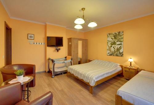 a bedroom with a bed and a chair and a tv at Willa pod Czantorią SPA Ustroń in Ustroń
