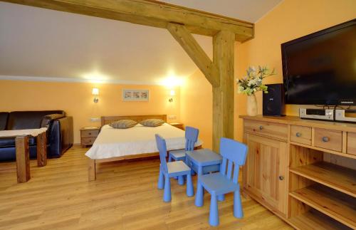 a bedroom with a bed with blue chairs and a flat screen tv at Willa pod Czantorią SPA Ustroń in Ustroń