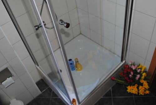 eine Dusche mit einer Glastür und einem Blumenstrauß in der Unterkunft Ferienwohnung Yachthafenperle in Kühlungsborn