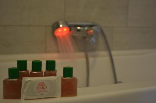 a group of four bottles of hot sauce in front of a bath tub at Hotel OK in Prizren